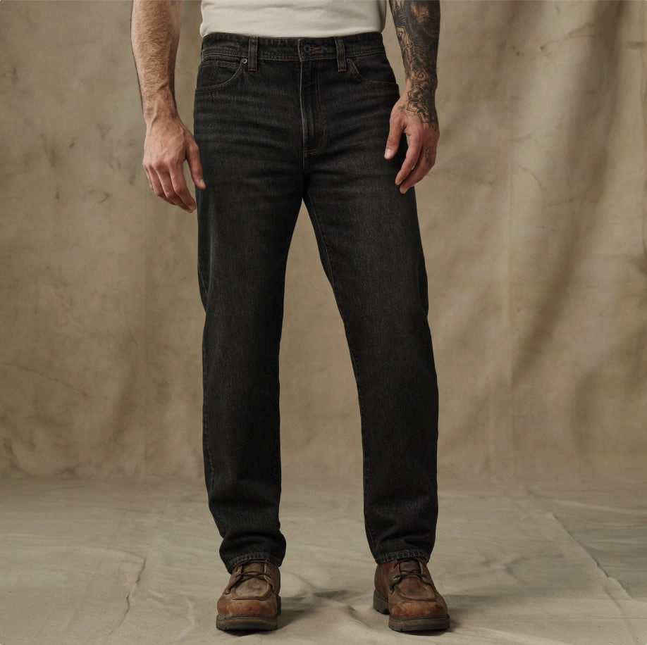 Man in dark work pants against a canvas backdrop