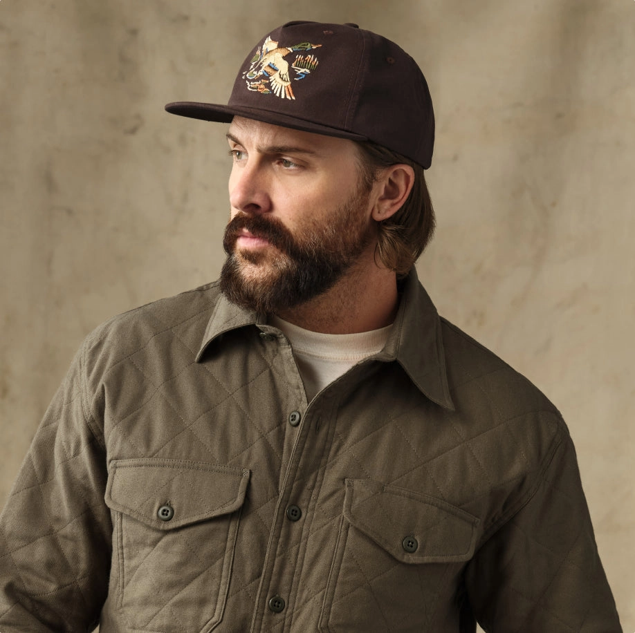 Bearded man in a cap and an olive overshirt