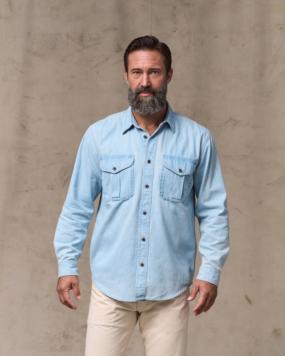 Man in a light blue denim shirt and cream pants