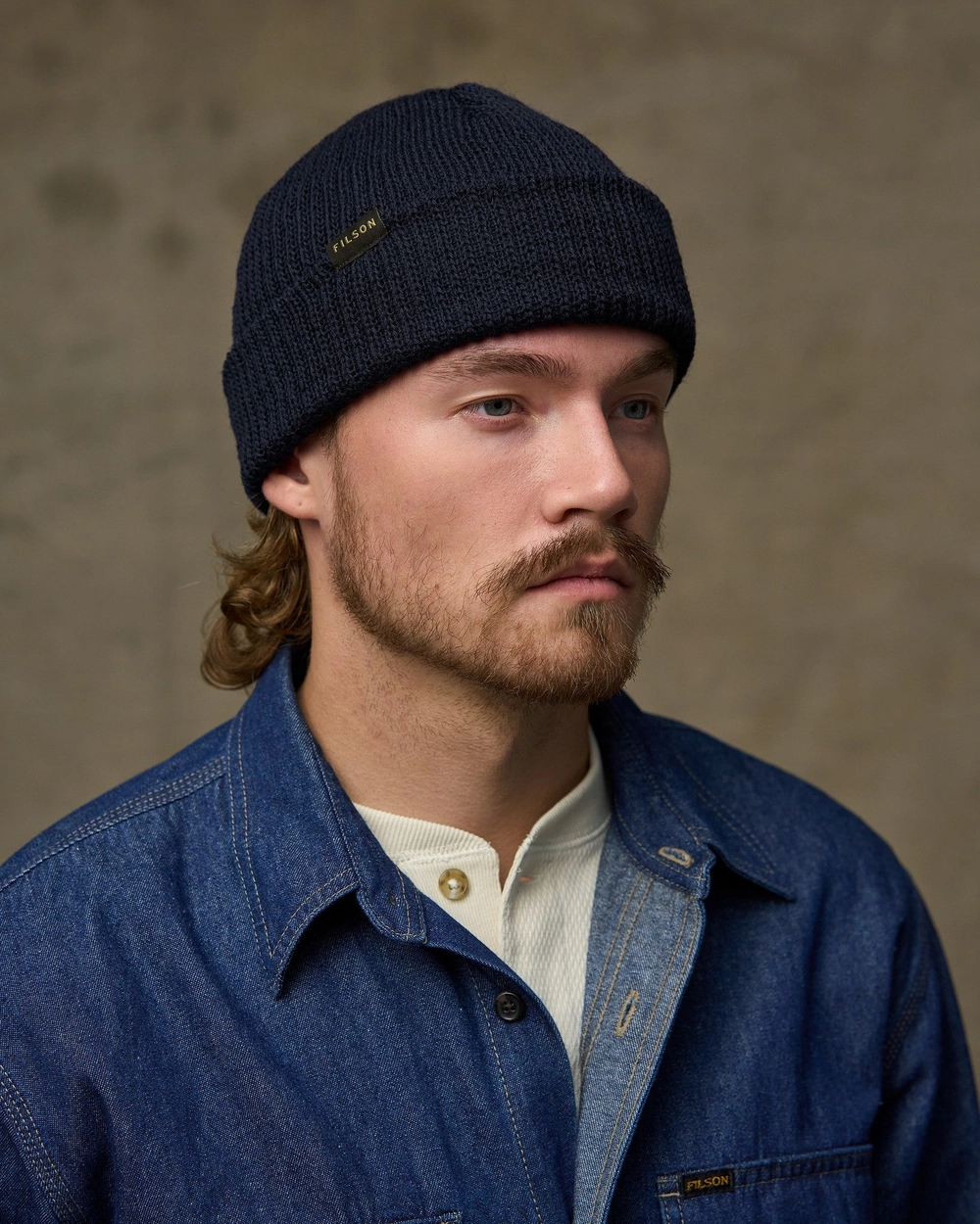 Man in a navy watch cap and a denim jacket