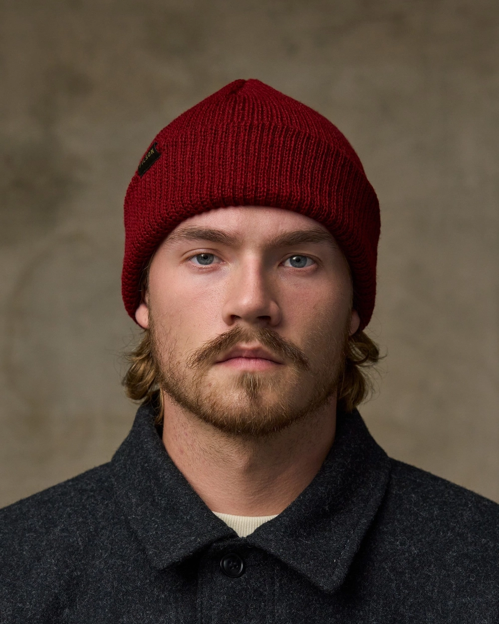 Man in a red watch cap and a dark wool coat